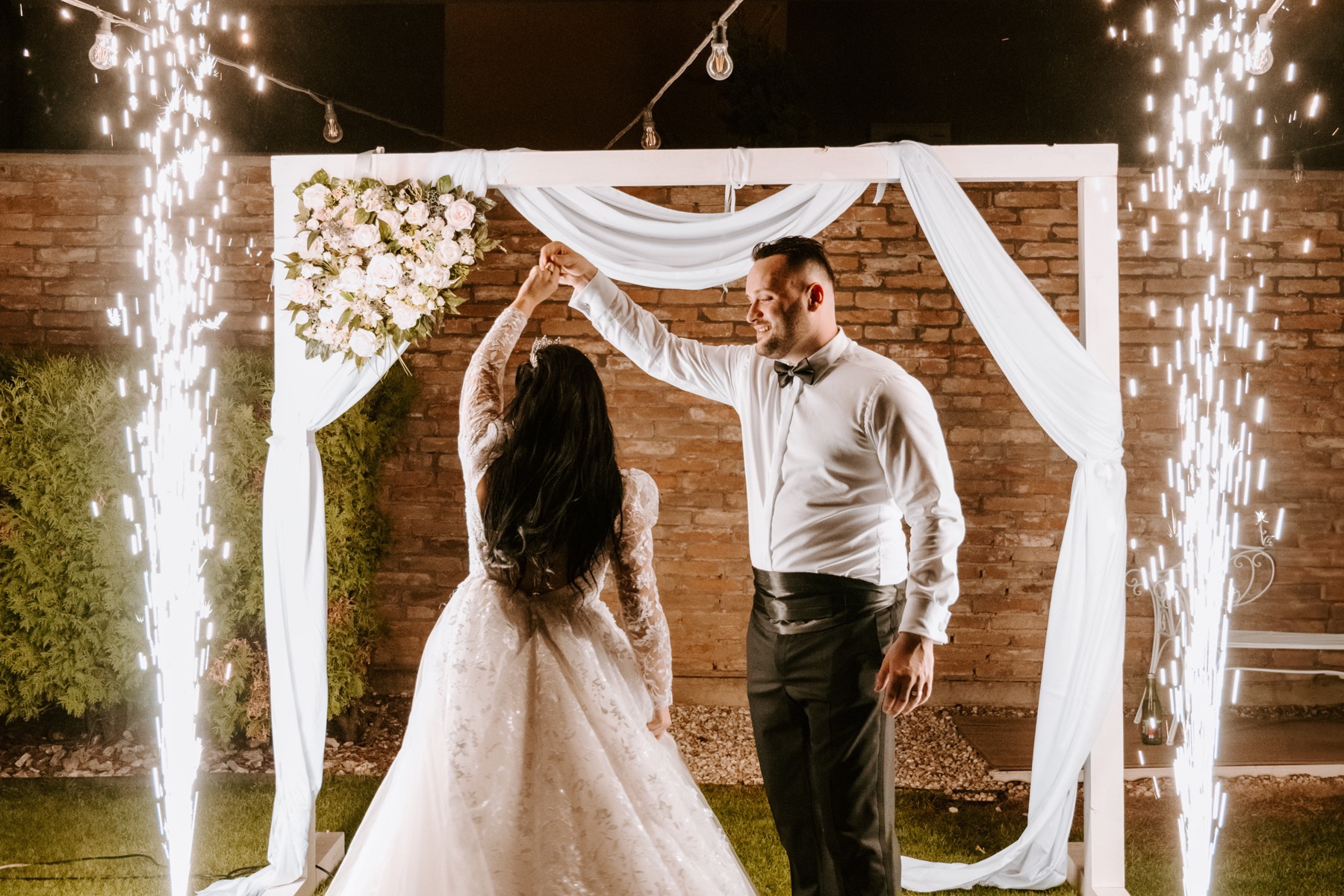 Newly married couple dancing between sparkling fountains